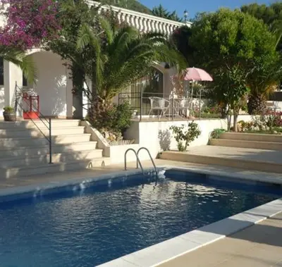 a swimming pool in front of a house with stairs at Suite in private villa view on sea in Castelldefels