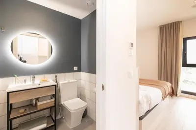 a white bedroom with a bed and a mirror at Canvas Sabadell Llac in Sabadell