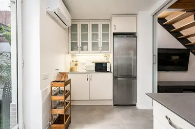 a kitchen with white cabinets and a stainless steel refrigerator at Encantador Apartamento con Terraza en Sants in Barcelona