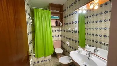 a bathroom with a sink and a toilet and green curtains at Maresme in Canet de Mar
