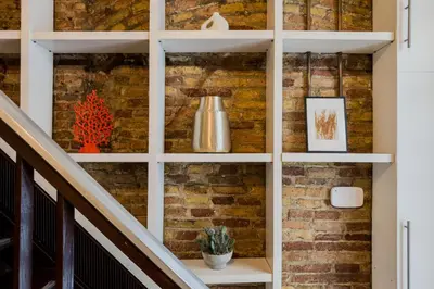 a brick wall with white shelves next to a staircase at Novus Homes Barcelona Plaza España in Barcelona