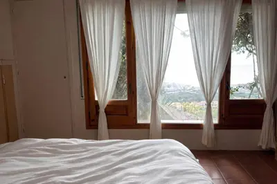 a bedroom with a bed and a large window at Casa Roca Lujo mediterráneo con piscina infinity in Sitges