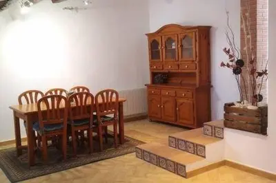 a dining room with a table and chairs and a wooden cabinet at Casa de pueblo con encanto in Arbós