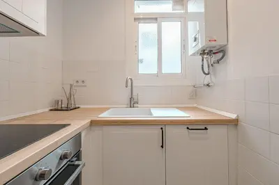 a white kitchen with a sink and a window at Apartamento reformado de 3 habitaciones en Sagrada Familia in Barcelona