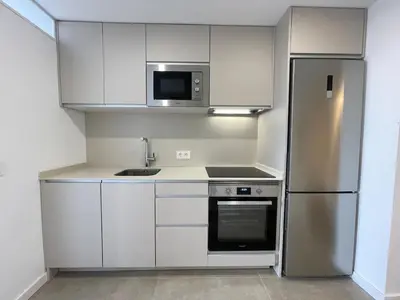 a kitchen with white cabinets and a stainless steel refrigerator at NEW 2-bedroom 2-bath, 5 min walk Metro L1-FIRA BCN in Hospitalet de Llobregat