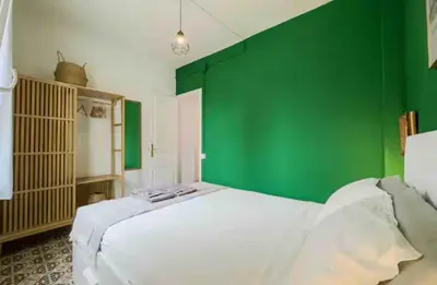 a bedroom with a green wall and a white bed at Apartment in BCN 2-1 in Hospitalet de Llobregat