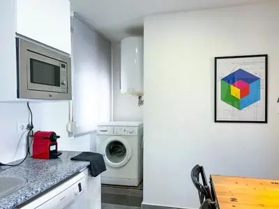 a kitchen with a washing machine and a microwave at Apartment Goya in Vilanova i la Geltrú