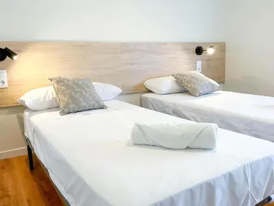 two beds in a room with white sheets and pillows at Apartment Goya in Vilanova i la Geltrú