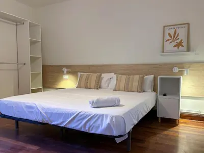 a bedroom with a large bed with white sheets at Apt Matisse in Vilanova i la Geltrú