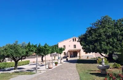 a white building with trees and a walkway at Masía con encanto para parar y desconectar in Castellví de la Marca