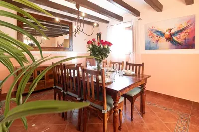 a dining room with a wooden table with flowers on it at Masía con encanto para parar y desconectar in Castellví de la Marca