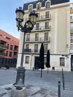 a street light with two umbrellas in front of a building at Apartamentos Barcelona - Iberia in Barcelona