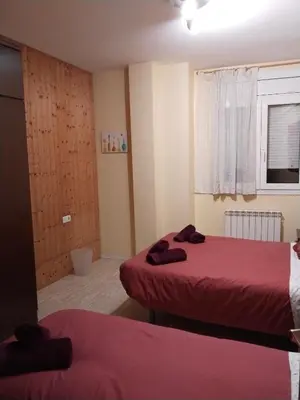 a room with two beds with red sheets and a window at Apartament Fira in Hospitalet de Llobregat