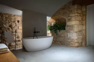 a bath tub in a room with a stone wall at Villa Mas Summit in Collsuspina