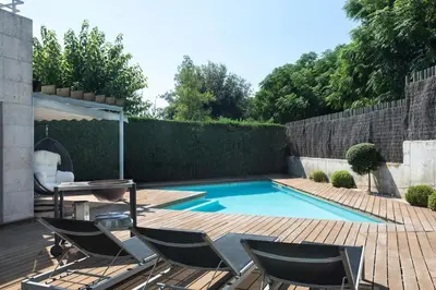 a swimming pool with chairs and a table on a wooden deck at TARRACO - Private Pool Villa in Arenys de Munt in Arenys de Munt