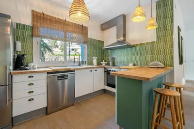 a kitchen with white cabinets and green tiles at Hauzify I Casa Olivella A in Olivella