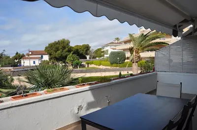 a table on a balcony with a view of a yard at Apartamento Mallorca, muy cerca de la playa in Sitges
