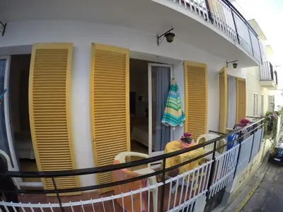 a balcony with yellow shutters on a building at Apartamentos Montserrat in Sitges