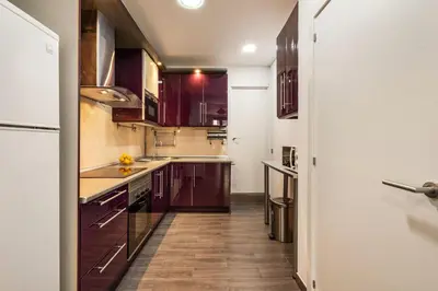 a kitchen with purple cabinets and wooden floors at Eixample Pedestrian Gem Balcony Bathtub AC in Barcelona
