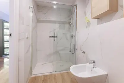 a white bathroom with a shower and a sink at ApartEasy mid-term ONLY for VACATIONS stays, EIXAMPLE CENTER in Barcelona