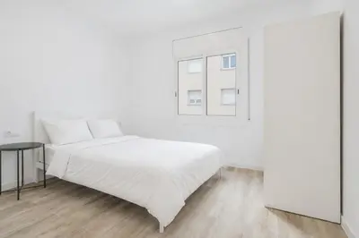 a white bedroom with a bed and a window at Apartahotel Sant Marti Suites in San Martín Sarroca