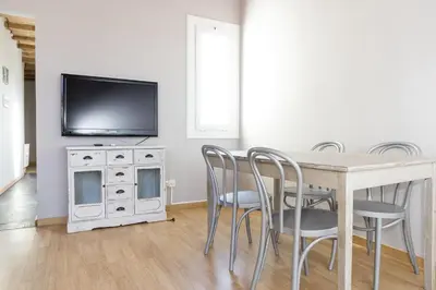 a dining room with a table and chairs and a tv at ApartEasy mid-term ONLY for VACATIONS stays, ATIC GRACIA in Barcelona
