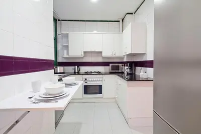 a white kitchen with white cabinets and appliances at Bcncaliu in Barcelona