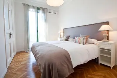 a white bedroom with a large bed and a window at Bcncaliu in Barcelona