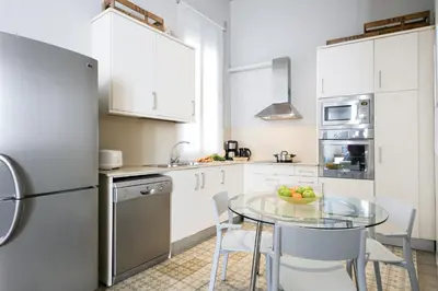 a kitchen with a glass table and white cabinets at Ola Living Gaudi in Barcelona
