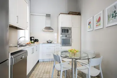 a kitchen with a glass table and white cabinets at Ola Living Gaudi in Barcelona