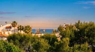 a view of the ocean from a city with trees at Apart Villa Cristina 5 min walk to the beach RoofTop Duplex 180 M2 Very Cared in Sitges