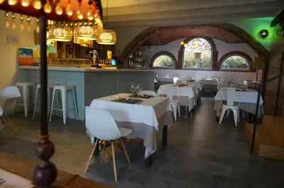 a restaurant with white tables and chairs and a bar at Hotel Can Ribalta in San Antonio de Vilamajor
