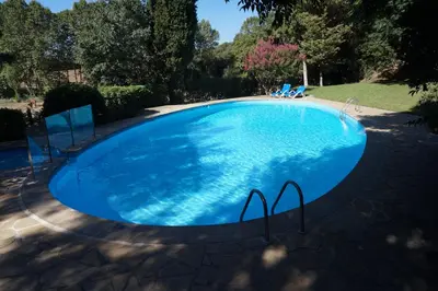 a large blue swimming pool with chairs in a yard at Hotel Can Ribalta in San Antonio de Vilamajor