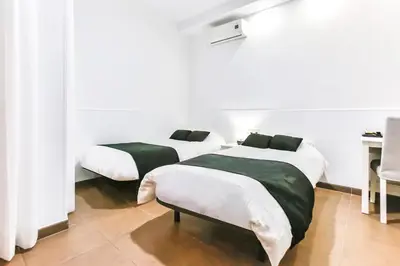 two beds in a room with white and green sheets at Laramond Barcelona Rooms in Barcelona
