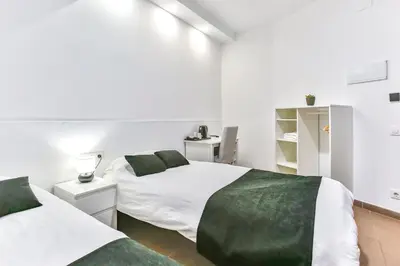 two beds in a room with white walls and green sheets at Laramond Barcelona Rooms in Barcelona