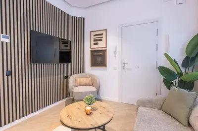 a living room with a table and chairs and a tv at Lodging Apartments Besos River B1 in Santa Coloma