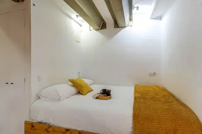 a small bedroom with a white bed with a yellow blanket at 2537 - AB Sant Antoni Studio in Barcelona