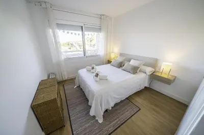 a white bedroom with a large bed and a window at HomeHolidaysRentals Pinedalovers - Costa Barcelona in Pineda de Mar