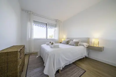 a white bedroom with a large bed and a window at HomeHolidaysRentals Pinedalovers - Costa Barcelona in Pineda de Mar