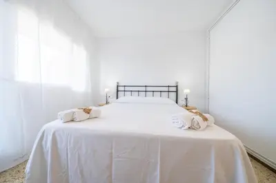 a white bedroom with a large white bed with towels on it at HomeHolidaysRentals Magic - Costa Barcelona in Pineda de Mar