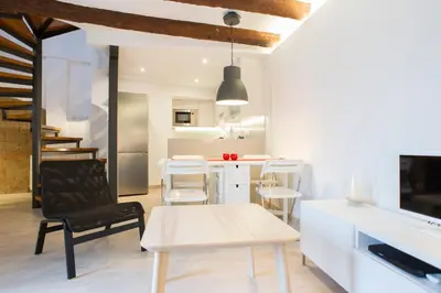 a kitchen and living room with a table and chairs at Casa De Poble Termes Romanes in Caldes de Montbui