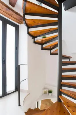 a spiral staircase in a house with wood treads at Casa De Poble Termes Romanes in Caldes de Montbui