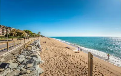 a beach with people on the sand and the ocean at Beautiful Apartment In Pineda De Mar in Pineda de Mar