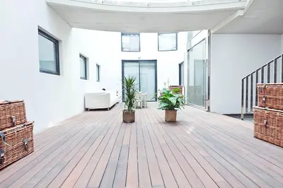 a large white room with two plants on a wooden floor at My Space Barcelona Private Pool Garden in Barcelona