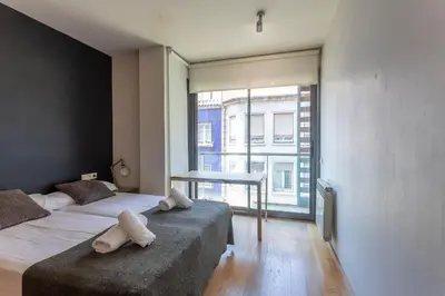 a bedroom with two beds and a table and a window at My Space Barcelona Penthouse Terrace in Barcelona
