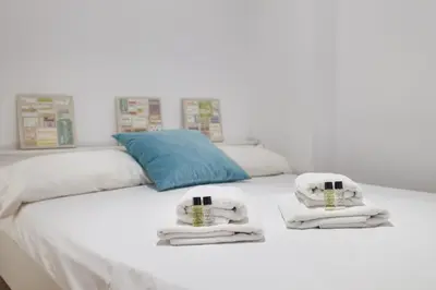 a white bed with towels and a blue pillow at Flateli Aribau in Barcelona