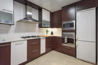a kitchen with brown cabinets and white appliances at Flateli Aribau in Barcelona