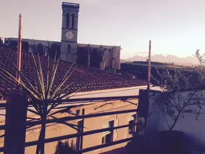 a building with a clock tower and a building with a fence at Apartments San Ignacio de Loyola in Manresa