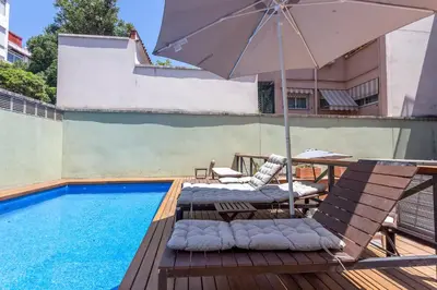 a patio with an umbrella and chairs next to a pool at My Space Barcelona Gracia Pool Terrace in Barcelona