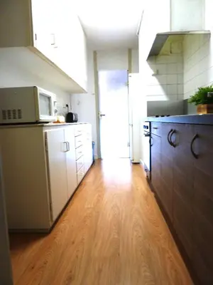 a kitchen with white cabinets and a wooden floor at Joanic Apartment Escorial in Barcelona